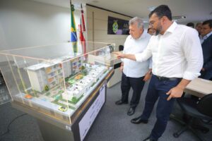 Governador Wilson Lima e o presidente da CEF, Carlos Vieira, observam maquete de conjunto habitacional (Foto: Secom)